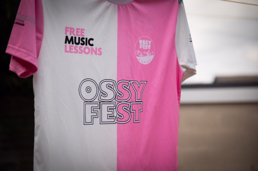 Ossyfest football shirt hung up, front view featuring Free Music Lessons and Ossyfest logos.